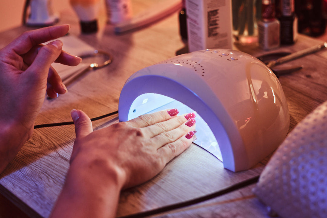 A hand under a UV lamp getting gel polish cured