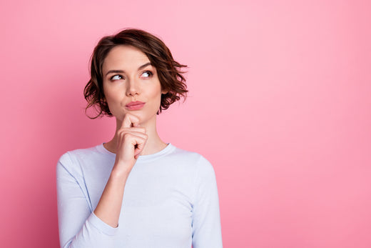 Curious woman standing in front of a pink background