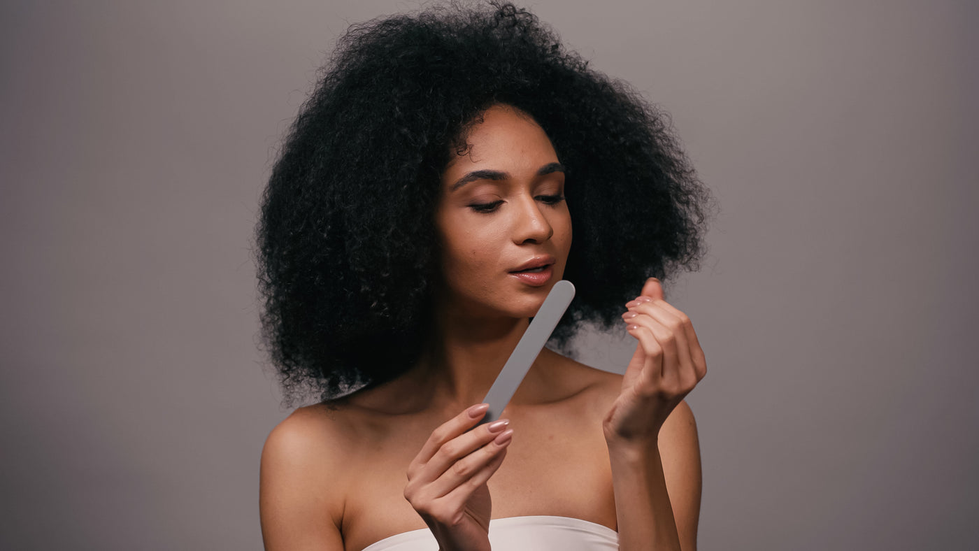 Woman at home golding a nail file while wrapped in a towel.